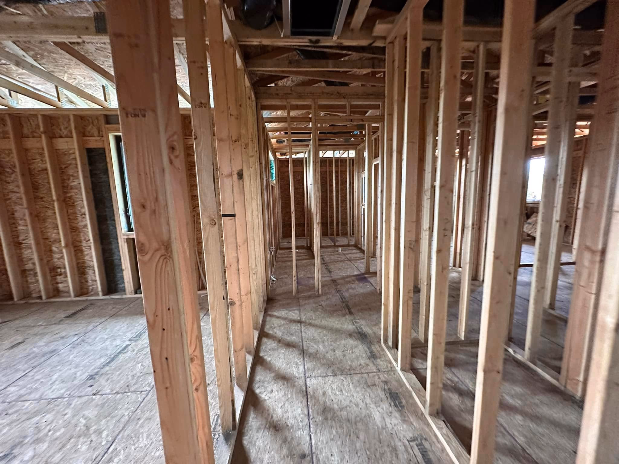 Interior of a house under construction showing wooden framing and exposed beams.